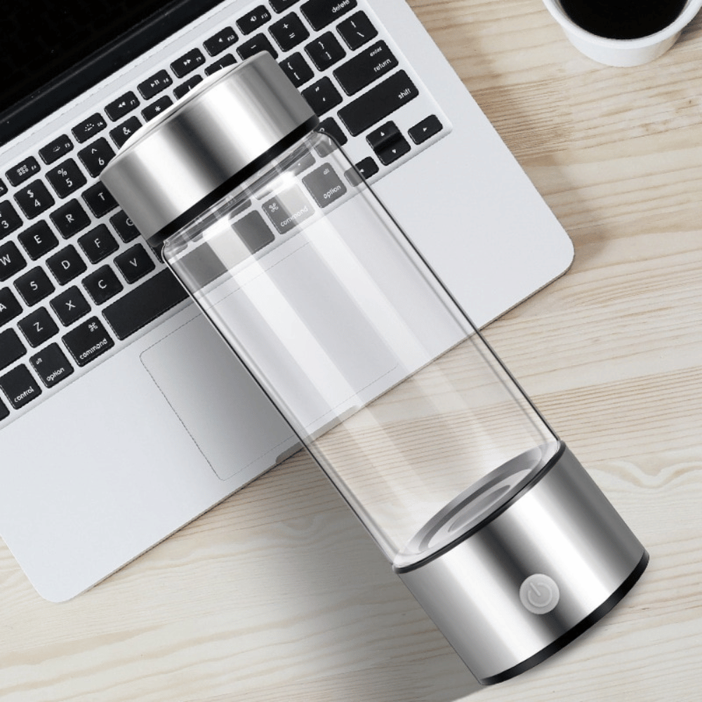 Portable hydrogen generator lying near a laptop, showcasing sleek design and USB portability.