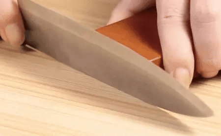 User sharpening kitchen knife with magnetic rolling sharpener featuring dual-angle wooden base
